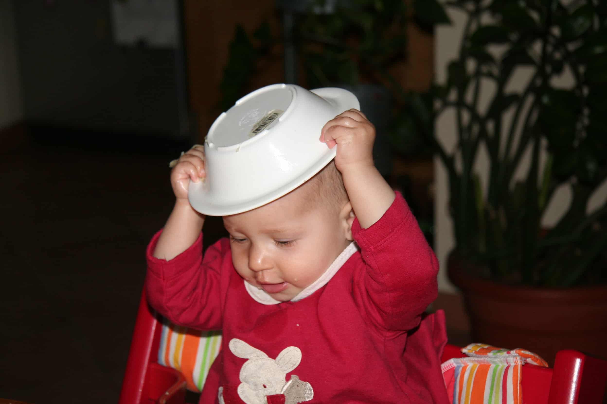 Bambina che fa autosvezzamento con piatto in testa