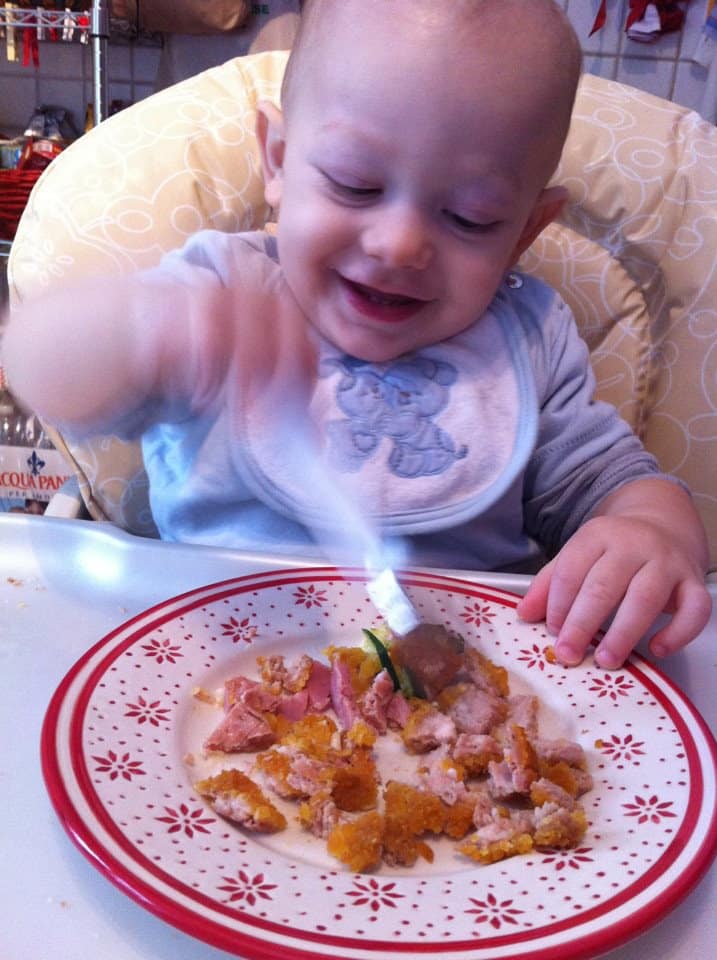 Bambino procede a svezzarsi da solo mangiando da un piatto