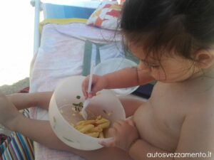 Bambina fa autosvezzamento in spiaggia